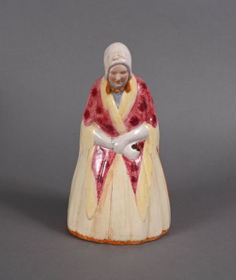 une vieille figurine représentant une femme vêtue d'une robe rouge et blanche