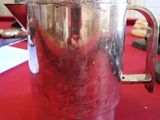 a silver pitcher on a red table with a red table cloth