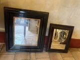 two framed pictures sitting on the floor next to a mirror