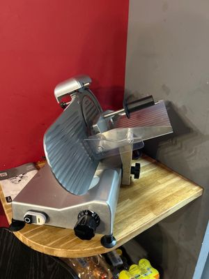 a meat slicer that is sitting on a wooden table