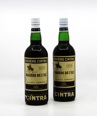 deux bouteilles de vin posées l'une à côté de l'autre sur une surface blanche