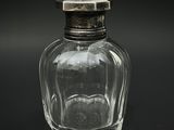 une bouteille en verre avec un bouchon argenté posée sur une surface noire