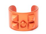 an orange cuff bracelet with studs and a button in the middle
