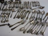 many spoons and forks laid out on a table