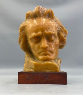 un gros plan sur une sculpture représentant une tête d'homme posée sur un socle en bois