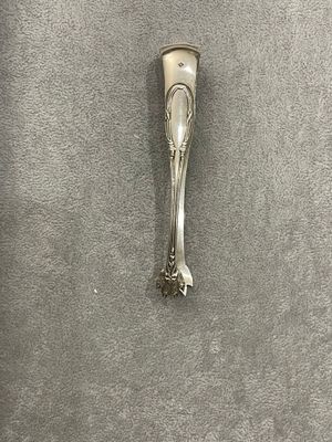 une cuillère en argent avec un manche, posée sur une surface grise