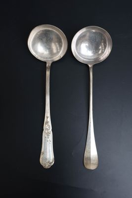 pair of silver spoons on a black surface with a black background