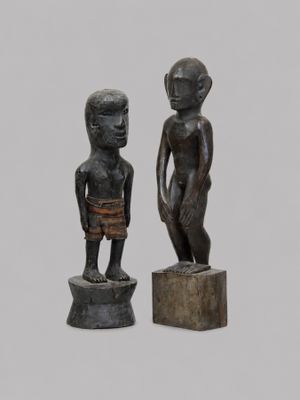 paire de statues en bois représentant un garçon et un autre garçon debout sur un socle
