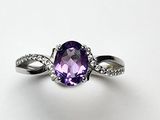 un gros plan d'une bague sertie d'une pierre violette et de diamants