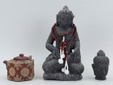 a statue of a person sitting in a meditation position next to a teapot