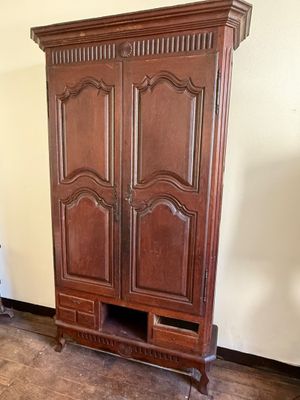 a wooden armoire in the corner of a room