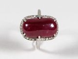 gros plan d'une bague avec une pierre rouge entourée de diamants