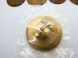 une pièce d'or sur laquelle est gravé un visage, posée sur un sac en plastique