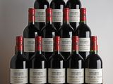 bottles of red wine sit on a wooden table in front of a white wall