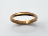 gros plan d'une bague en or sur une surface blanche
