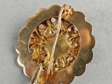 an image of a gold brooch with a flower design on it