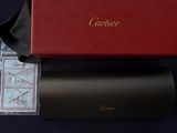 une boîte rouge ornée d'un logo doré, à côté d'une paire de lunettes