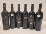 six bottles of wine are lined up in a row on a table