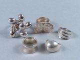 Plusieurs bagues en argent sont posées sur une table.