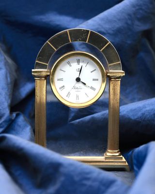a small gold clock sitting on a blue cloth