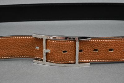 brown leather belt with a silver buckle on a gray surface