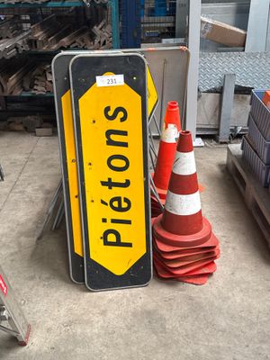 a yellow and black stop sign next to a red and white traffic cone