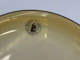 a yellow bowl with a black rim on a white table