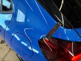 a close up of a blue car with a sticker on the back of it