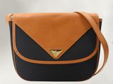 un sac à bandoulière noir et fauve orné d'un triangle doré sur le devant