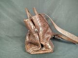 brown leather purse with strap on a green background