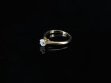 an engagement ring with a single stone on a black background