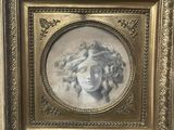 un tableau représentant le visage d'une femme, dans un cadre doré