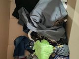 a cardboard box filled with clothes and a stuffed animal