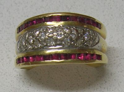 une photo d'une bague sertie d'un diamant et d'un rubis posée sur une table