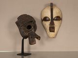 deux masques en bois exposés sur une table en verre