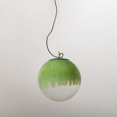 une boule en verre verte et blanche suspendue à un fil noir