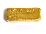 un lingot d'or posé sur une surface blanche, sur fond blanc