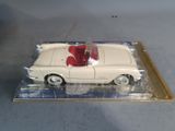 a white toy car with a red top in a clear box