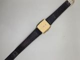 gros plan d'une montre sur une surface blanche avec un bracelet noir
