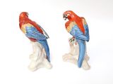 two figurines of parrots sitting on a tree branch
