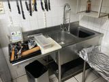 une cuisine équipée d'un évier, d'une cuisinière et d'autres ustensiles accrochés au mur