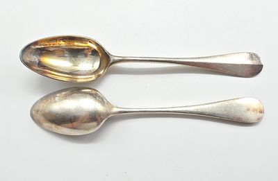 une paire de cuillères en argent posées sur une surface blanche, sur fond blanc