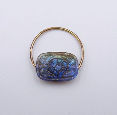 un gros plan d'une bague en or ornée d'une perle de verre bleue