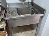 un évier dans un coin de la cuisine, avec un sac poubelle par terre