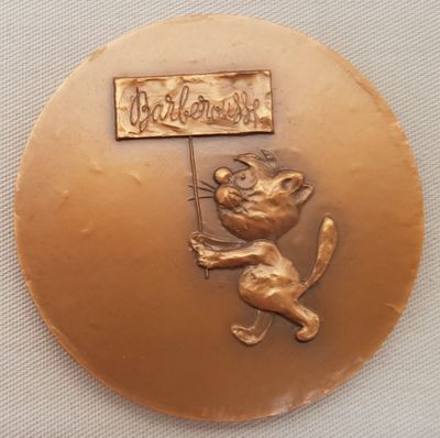 une médaille d'or sur laquelle figure un chat tenant une pancarte