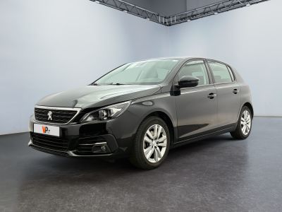 La voiture grise est garée dans une grande pièce au sol noir.