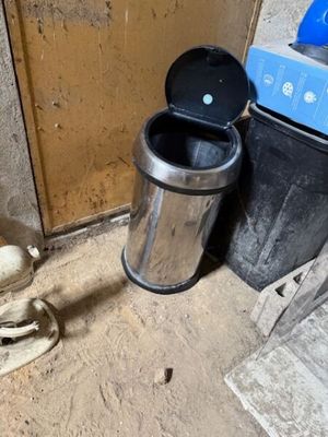 une poubelle posée à côté d'une autre poubelle, par terre