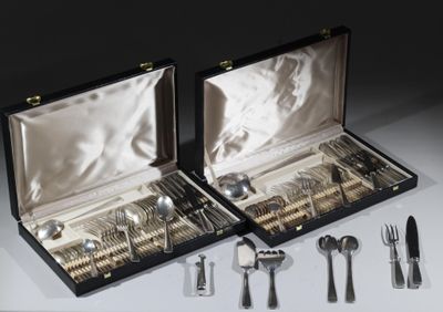 des couverts dans un coffret posé sur une table contenant d'autres couverts