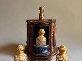 une figurine miniature représentant un flacon de parfum et deux salières posées sur une table