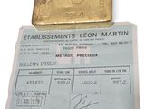 un morceau d'or posé sur une feuille de papier sur laquelle est représenté un lingot d'or